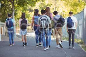 Rear vie of school kids walking on road in campus