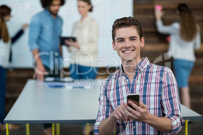 Smiling business executive using mobile phone in office