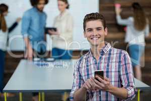 Smiling business executive using mobile phone in office