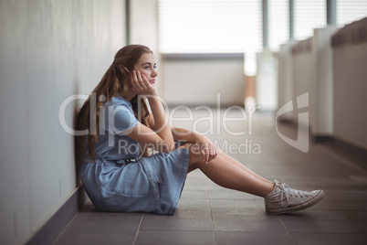 Sad schoolgirl sitting in corridor