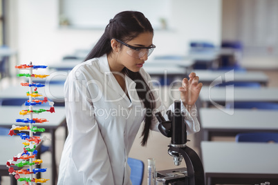 Attentive schoolgirl experimenting microscope slide in laboratory