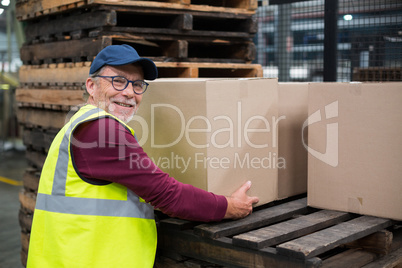Factory worker loading cardboard boxes on trolley