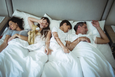 Parents and kids sleeping on bed