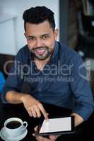 Portrait of smiling business executive using digital tablet while having cup of tea