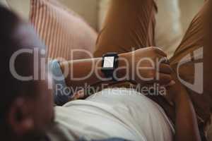 Man lying on sofa and checking his smartwatch