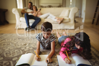 Kids doing homework while lying on rug
