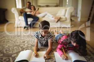 Kids doing homework while lying on rug