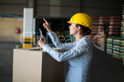 Female factory worker maintaining record on mobile phone in factory