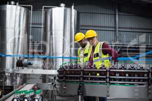 Factory workers monitoring cold drink bottles at drinks production plant