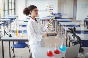 Attentive schoolgirl experimenting molecule model in laboratory