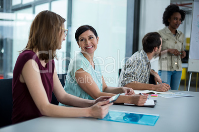 Smiling business executives interacting with each other during meeting
