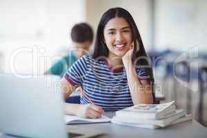 Portrait of happy schoolgirl studying in classroom