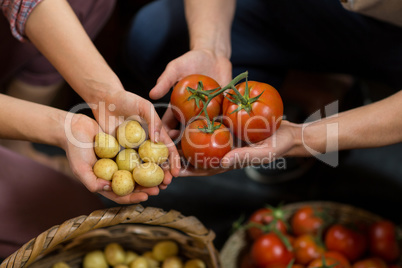 Woman and man vendors holding tomatoes and potatoes at grocery store
