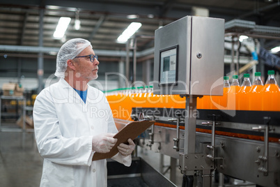 Factory engineer maintaining record on clipboard in factory