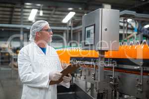 Factory engineer maintaining record on clipboard in factory