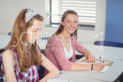 Portrait of happy schoolgirl sitting in classroom