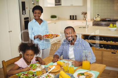 Portrait of happy woman serving food to the family