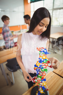 Smiling schoolgirl examining the molecule model in laboratory