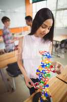 Smiling schoolgirl examining the molecule model in laboratory