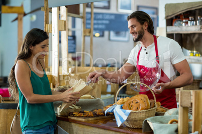 Smiling bakery staff giving parcel to a female customer at counter