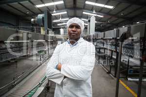 Factory engineer standing with arms crossed in bottle factory