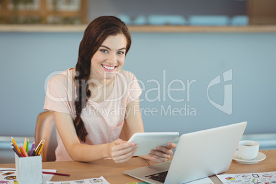 Portrait of beautiful business executive sitting at desk and using digital tablet
