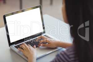 Schoolgirl using laptop in classroom