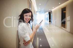 Portrait of female executive using mobile phone in corridor