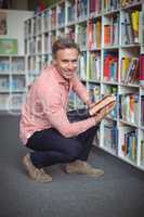 Portrait of happy school teacher selecting book in library