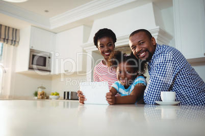Portrait of parents and daughter using digital tablet in kitchen