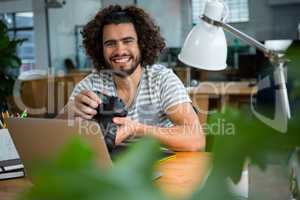 Smiling graphic designer looking at pictures in digital camera