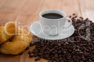 Coffee with roasted coffee beans and croissant