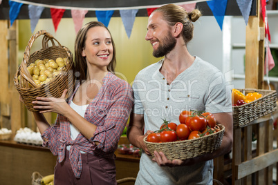 Woman and man vendors holding a basket of tomatoes and potatoes