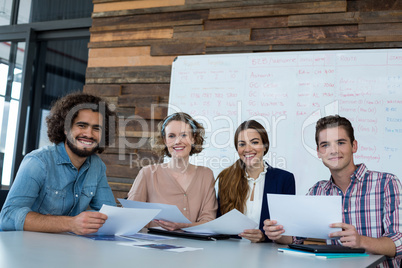 Smiling business executives sitting in office with document