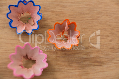 Colored pencil shavings in a flower shape on wooden background