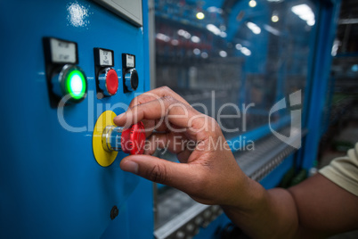 Hands of factory worker turning the control knob on the board