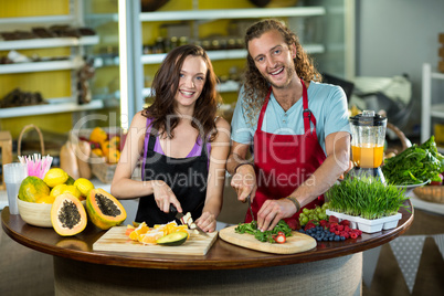 Two shop assistant chopping vegetables and fruits at counter