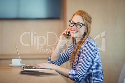 Female graphic designer talking on mobile phone while working in office