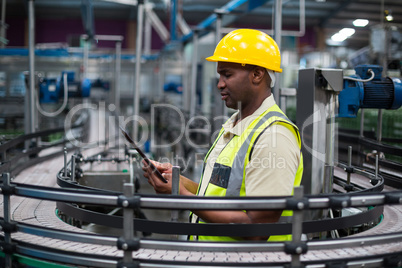 Factory worker using a digital tablet near the production line