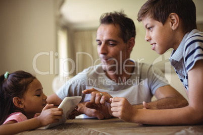 Father and kids using digital tablet in living room