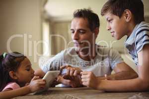 Father and kids using digital tablet in living room