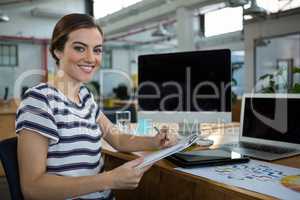 Smiling female designer writing on clipboard