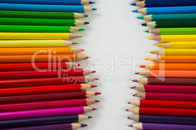 Colored pencils arranged in a row on white background