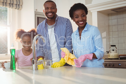 Portrait of family washing utensils in kitchen sink