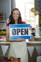 Female shop assistant holding open sign board