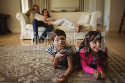 Parents and kids watching television in living room