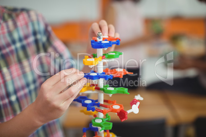 Mid section of schoolboy examining the molecule model in laboratory