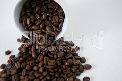 Roasted coffee beans spilling out of cup