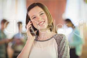 Smiling schoolgirl talking on mobile phone in corridor