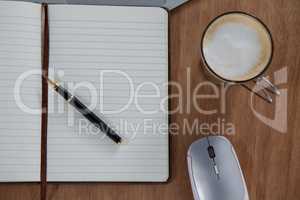 Close-up of coffee, oraginser, pen and mouse